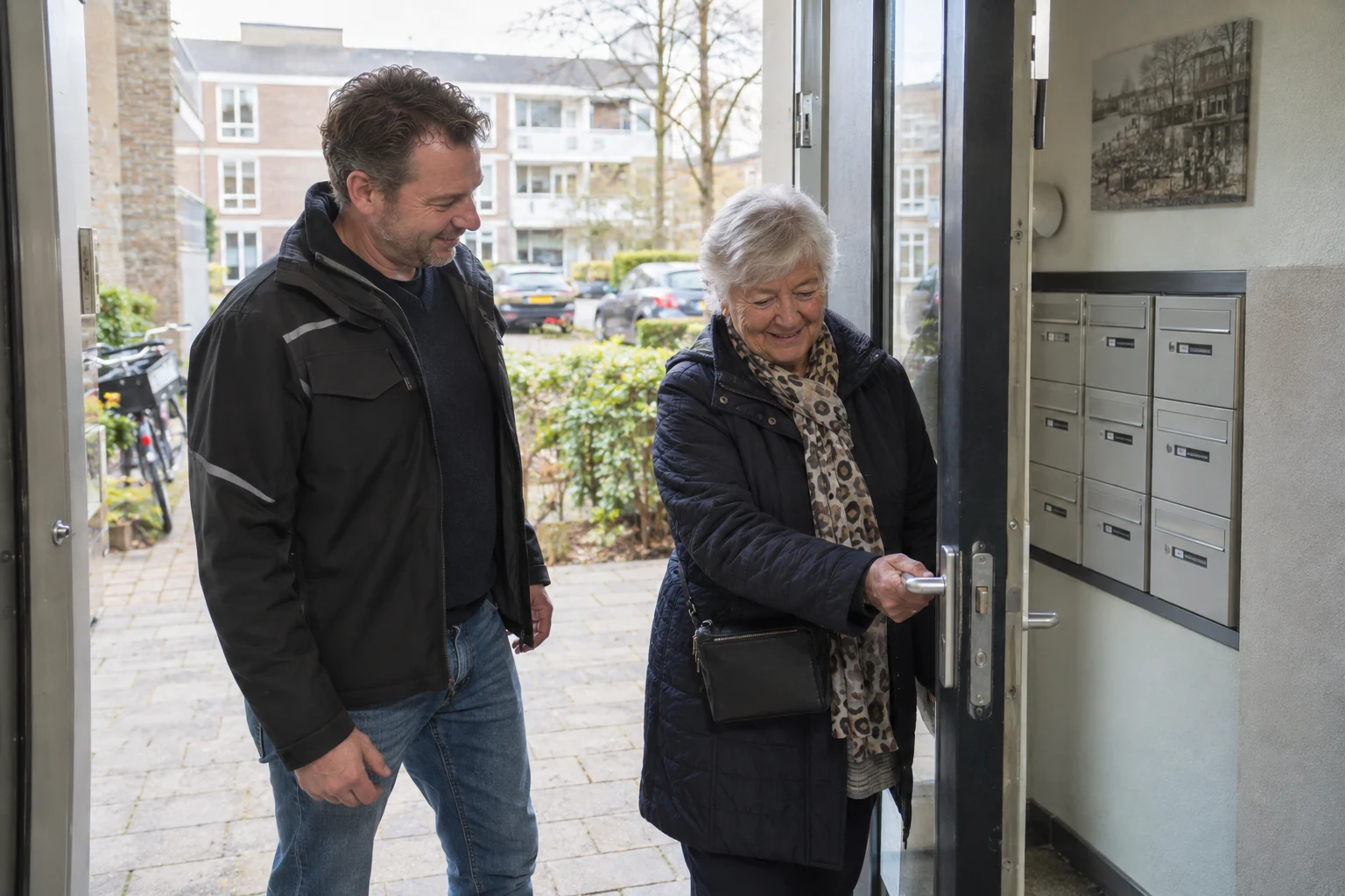 Een bewoner probeert de gemeenschappelijke deur terwijl een medewerker meekijkt.