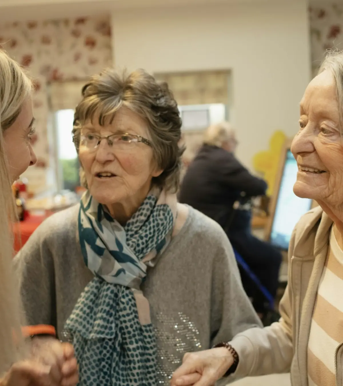 Drie vrouwen voeren een gesprek in een gemeenschappelijke ruimte.