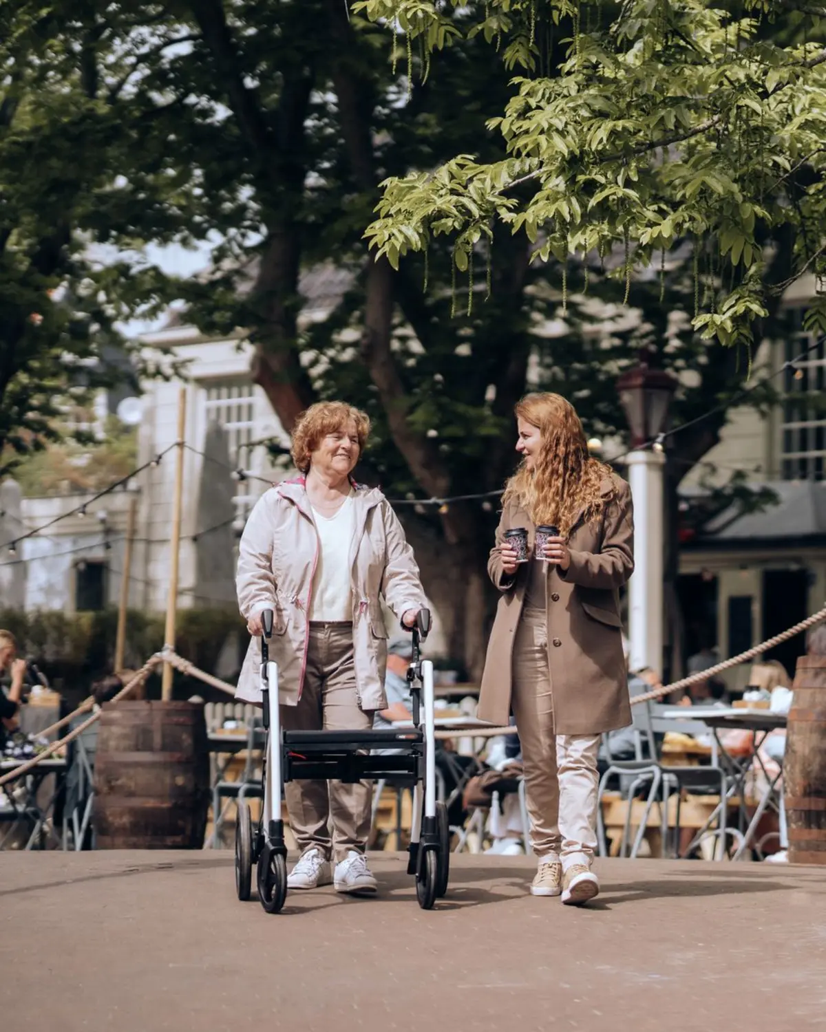 Een oudere vrouw loopt met een rollator naast een jongere vrouw door Amsterdam.
